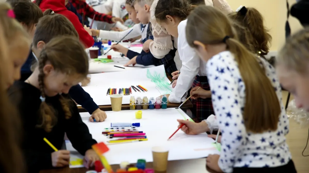 Young children doing a hands-on arts activity with their teacher in a classroom
